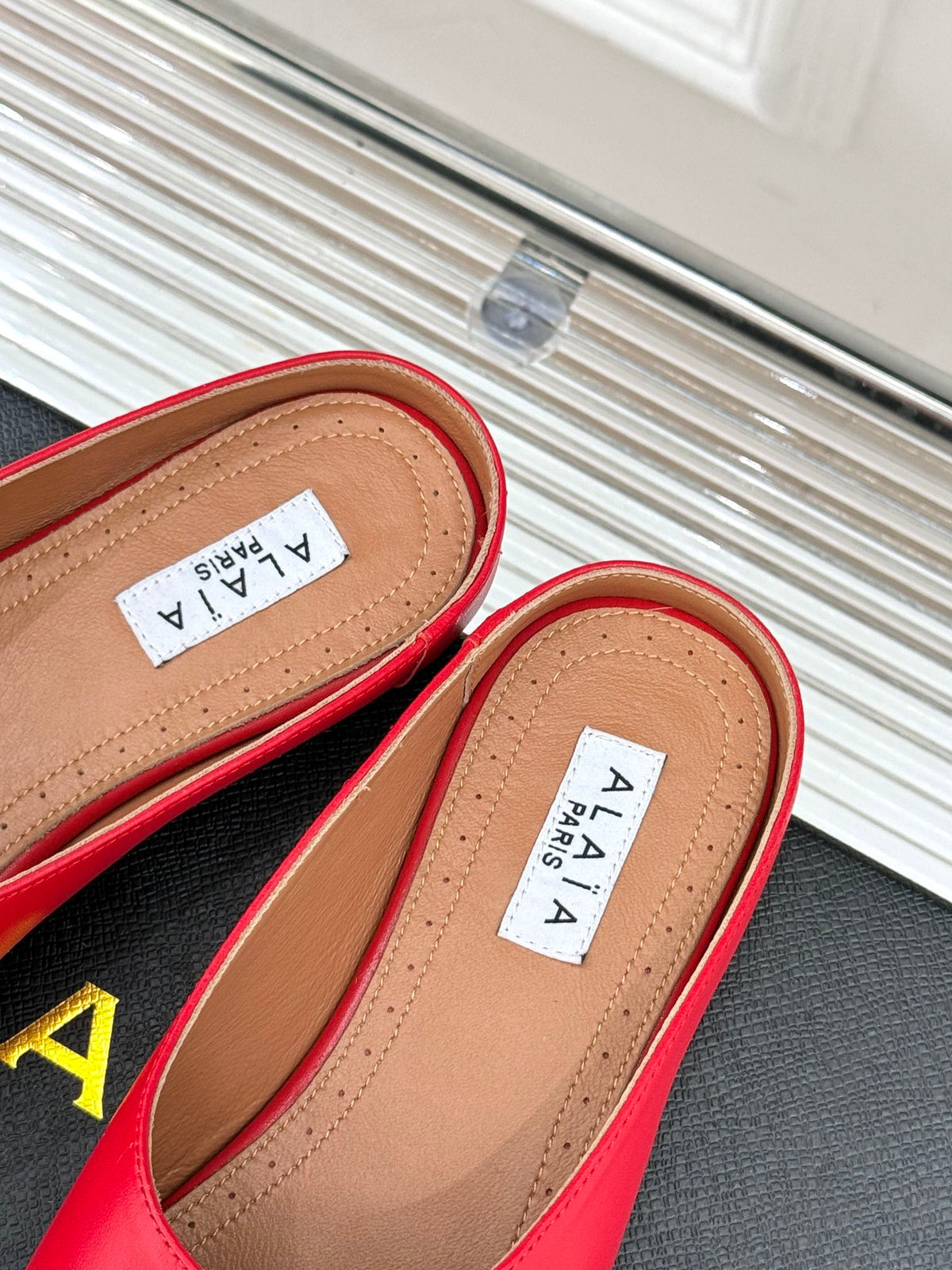 ALAIA FLAT MULE IN CRIMSON RED LAMBSKIN WITH GOLD HARDWARE